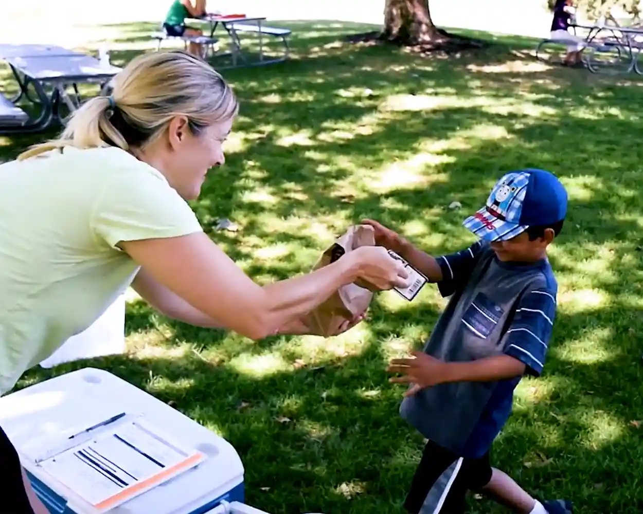 A volunteer serving free lunches to kids.